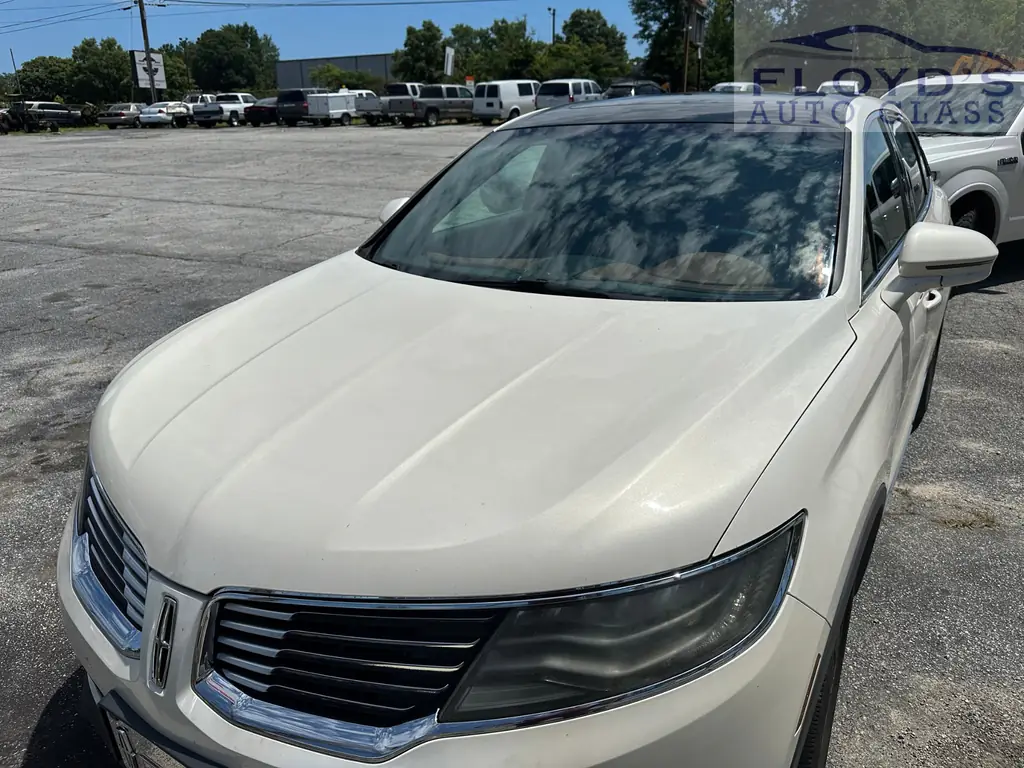 A white Lincoln SUV with a newly fitted windshield, photographed across the hood